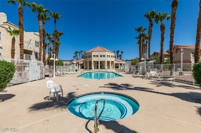 community pool featuring a hot tub, a residential view, fence, and a patio