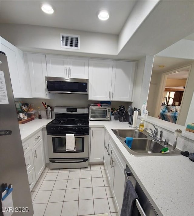 kitchen with a sink, visible vents, white cabinetry, light countertops, and appliances with stainless steel finishes