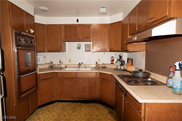 kitchen with white microwave, under cabinet range hood, a sink, light countertops, and stovetop