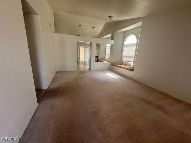 unfurnished room with vaulted ceiling and light carpet