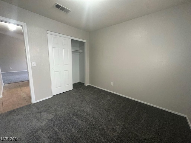 unfurnished bedroom featuring dark colored carpet and a closet