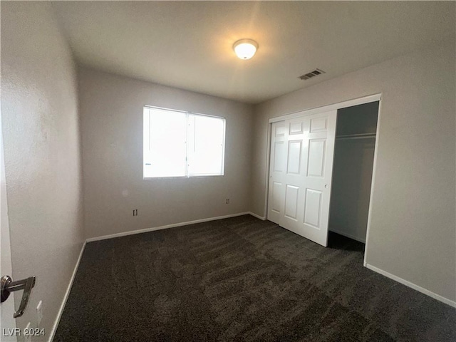 unfurnished bedroom featuring a closet and dark colored carpet