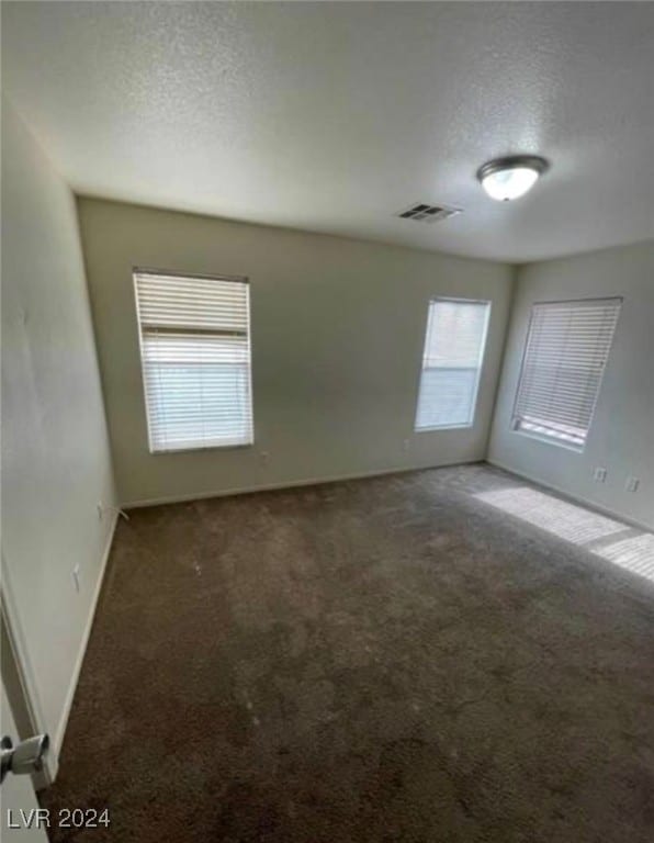 carpeted empty room with a textured ceiling