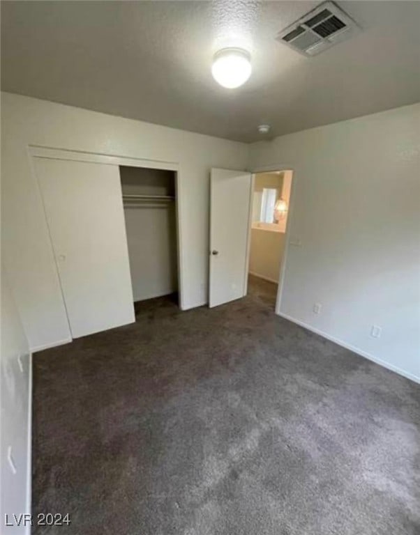 unfurnished bedroom featuring a closet and dark colored carpet