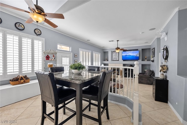 dining room featuring ceiling fan, crown molding, light tile patterned flooring, and a healthy amount of sunlight