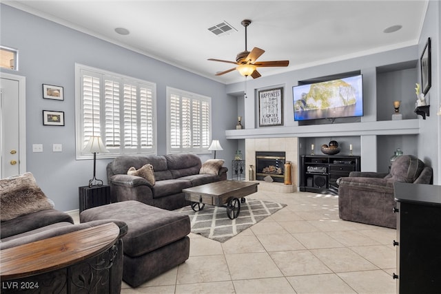 tiled living room featuring ceiling fan, ornamental molding, and a tile fireplace