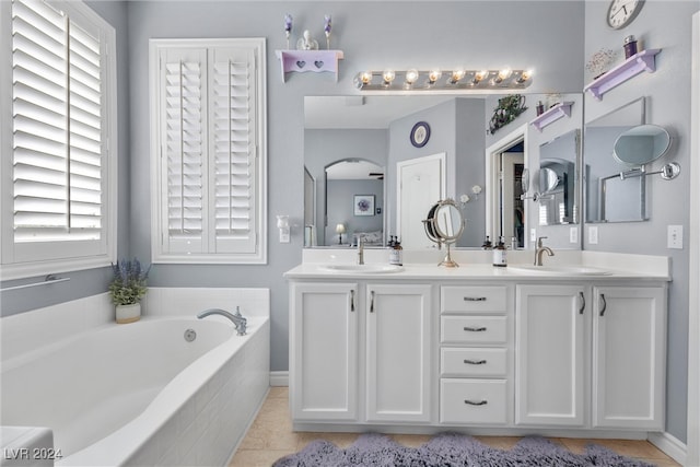 bathroom featuring tiled tub, dual bowl vanity, and tile patterned floors