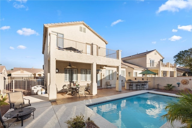 rear view of house with a balcony, a patio, a fenced in pool, and ceiling fan