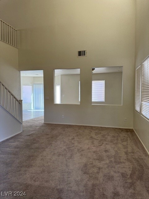 spare room with a towering ceiling and carpet flooring