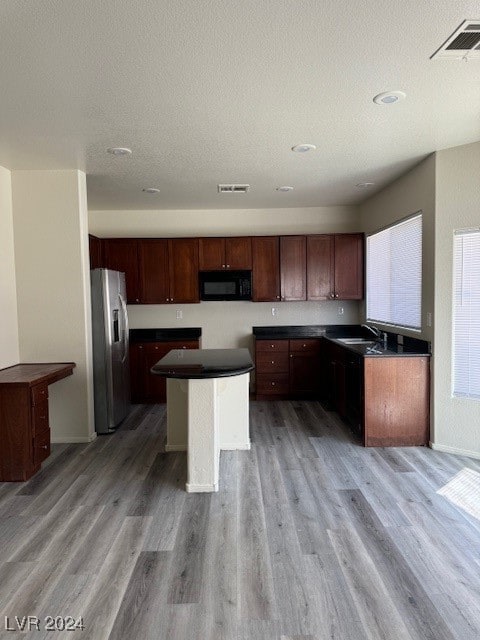 kitchen featuring hardwood / wood-style floors, sink, stainless steel refrigerator with ice dispenser, a textured ceiling, and a kitchen island