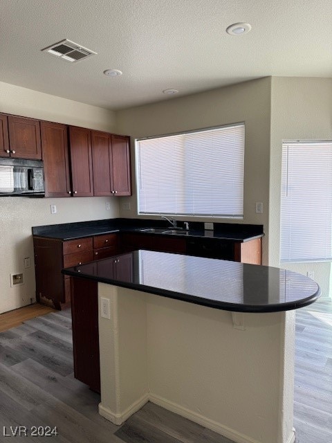 kitchen featuring sink, a center island, hardwood / wood-style floors, and a textured ceiling