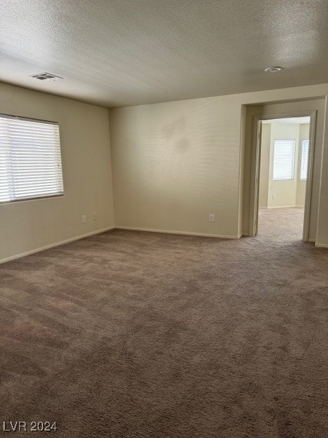 empty room with a textured ceiling and light carpet