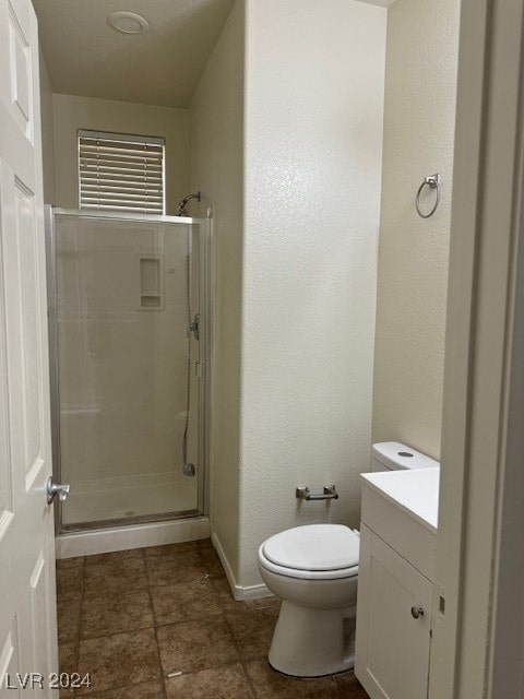 bathroom with tile patterned flooring, a shower with door, vanity, and toilet