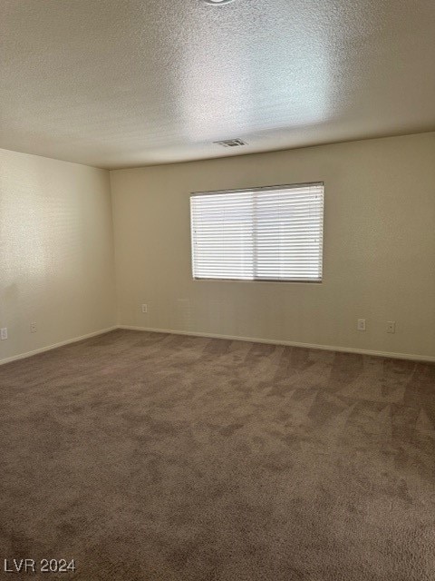 carpeted empty room with a textured ceiling