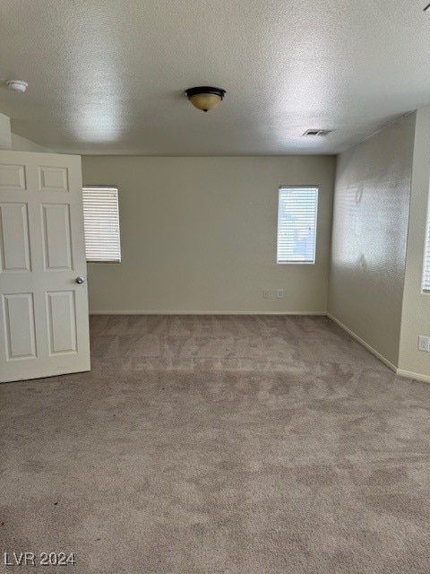 unfurnished room featuring a textured ceiling and carpet floors