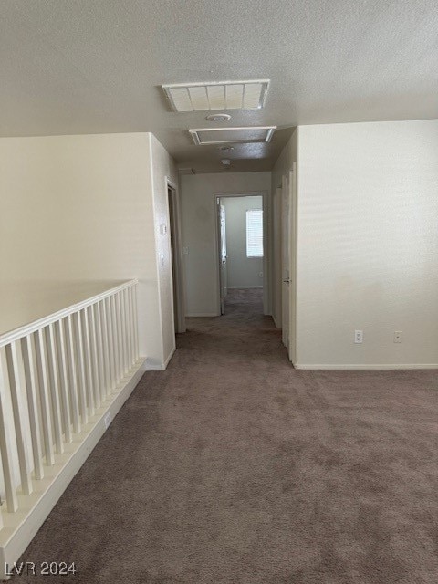 hall with a textured ceiling and carpet