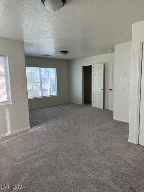 empty room with carpet and a textured ceiling