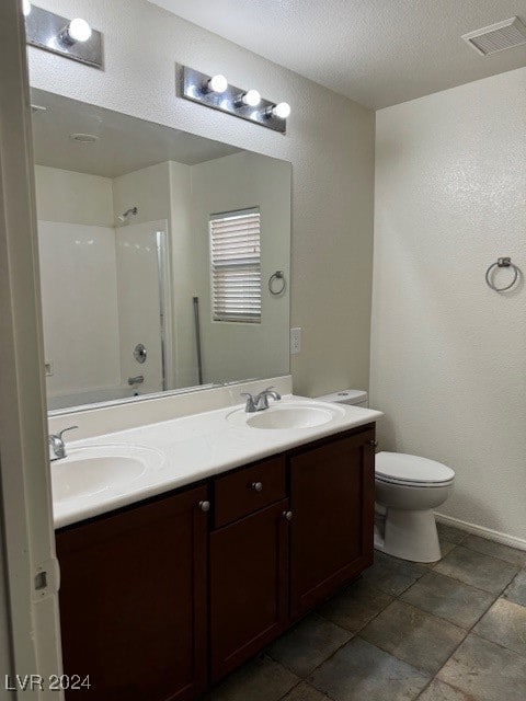 bathroom featuring tile patterned floors, dual bowl vanity, a textured ceiling, and toilet