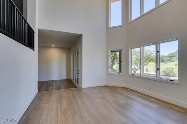 interior space with wood finished floors, baseboards, and a towering ceiling