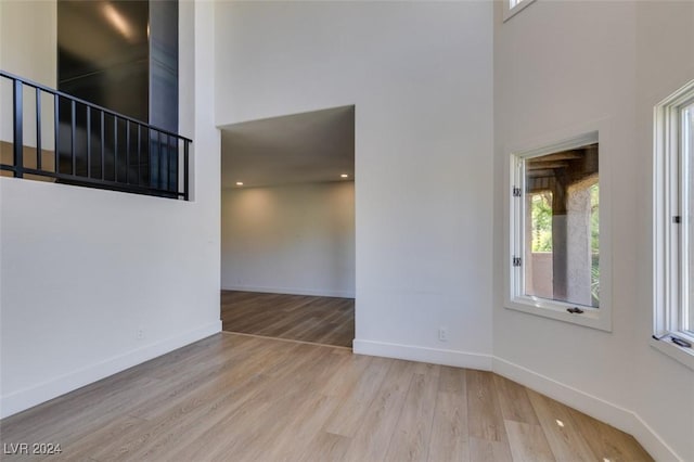 spare room featuring stairway, wood finished floors, baseboards, and a towering ceiling