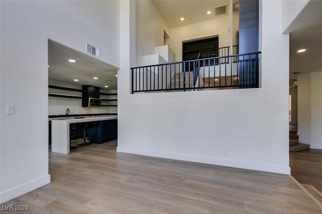 interior space featuring wood finished floors, visible vents, baseboards, stairs, and a towering ceiling