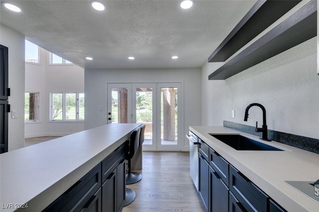 kitchen featuring a textured ceiling, light countertops, light wood finished floors, and a sink