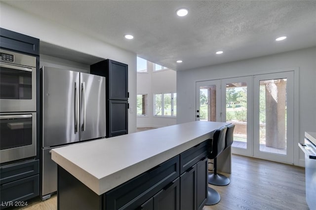 kitchen featuring light wood-style flooring, recessed lighting, light countertops, appliances with stainless steel finishes, and a textured ceiling