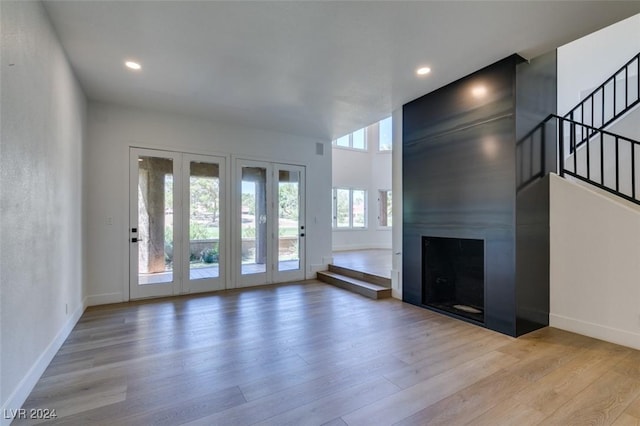 unfurnished living room featuring stairs, wood finished floors, baseboards, and a fireplace