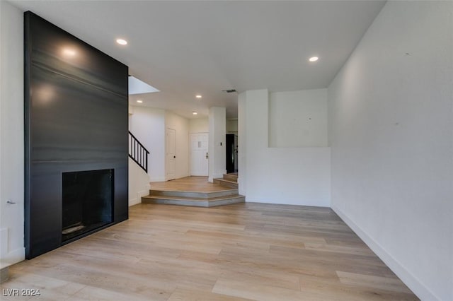 unfurnished living room with visible vents, recessed lighting, light wood-type flooring, and stairs