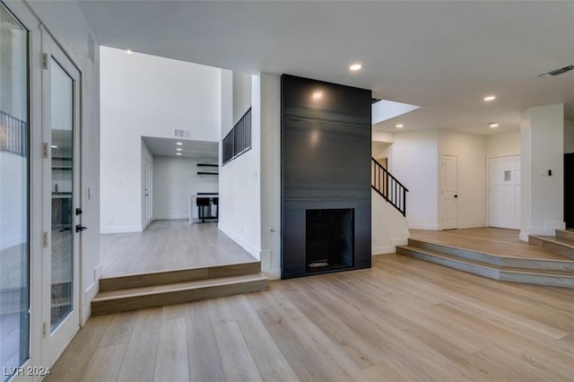 unfurnished living room with visible vents, a large fireplace, stairway, recessed lighting, and wood finished floors