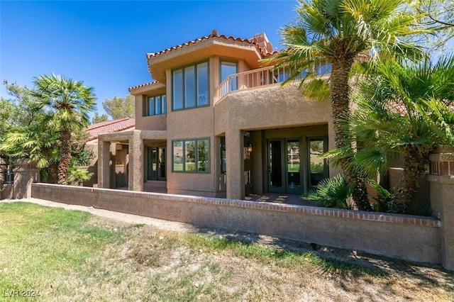 rear view of property featuring stucco siding, a balcony, french doors, and a tiled roof