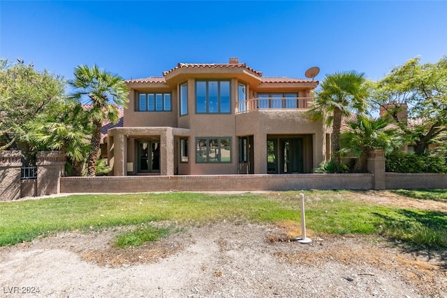 back of house featuring a tiled roof, a balcony, and stucco siding