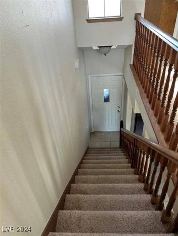 stairway featuring carpet and a towering ceiling