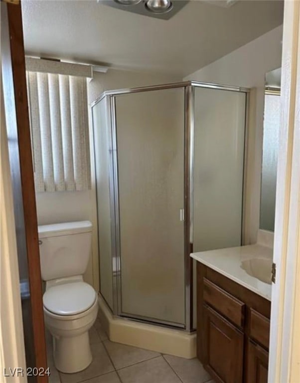 bathroom with tile patterned floors, a shower with door, vanity, and toilet