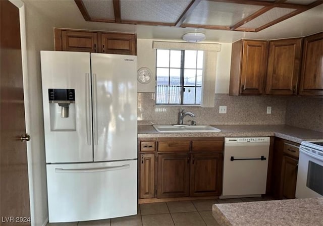 kitchen with sink, backsplash, light tile patterned flooring, and white appliances