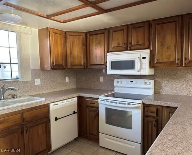 kitchen with sink, white appliances, light tile patterned floors, and tasteful backsplash