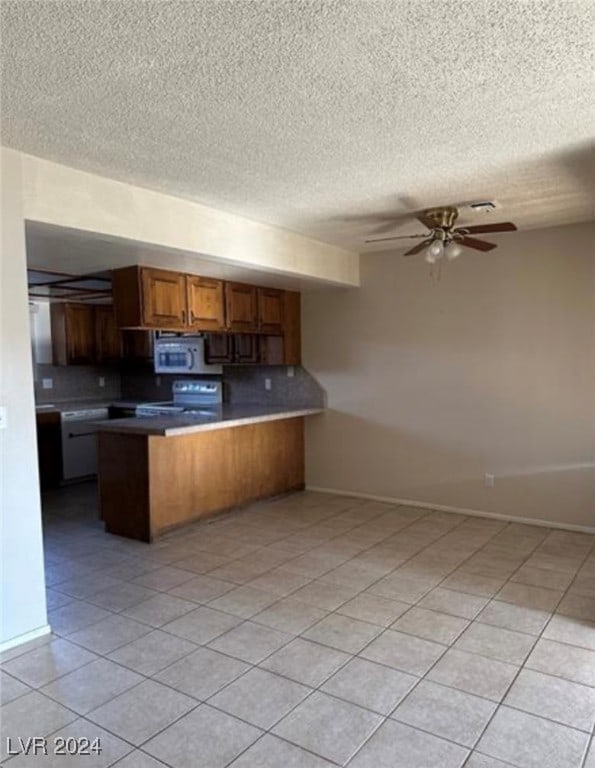 kitchen featuring ceiling fan, kitchen peninsula, stove, and light tile patterned floors