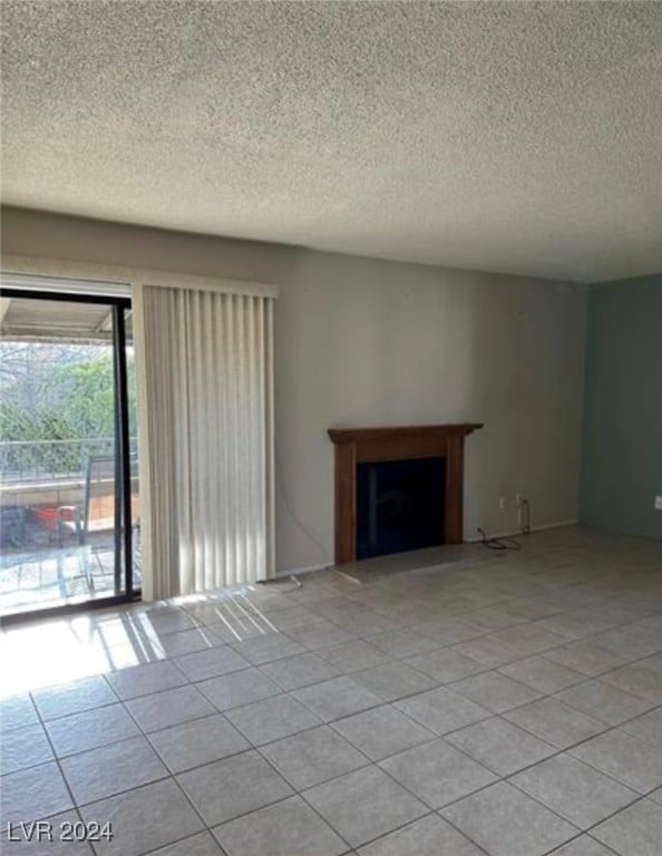 unfurnished living room with light tile patterned flooring and a textured ceiling