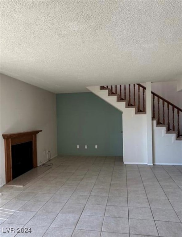 unfurnished living room with a textured ceiling and light tile patterned floors