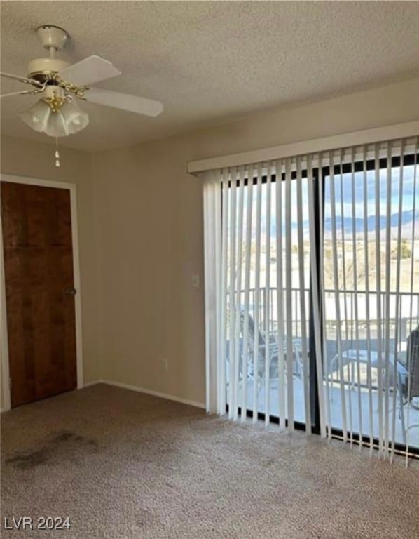 carpeted empty room with ceiling fan and a textured ceiling