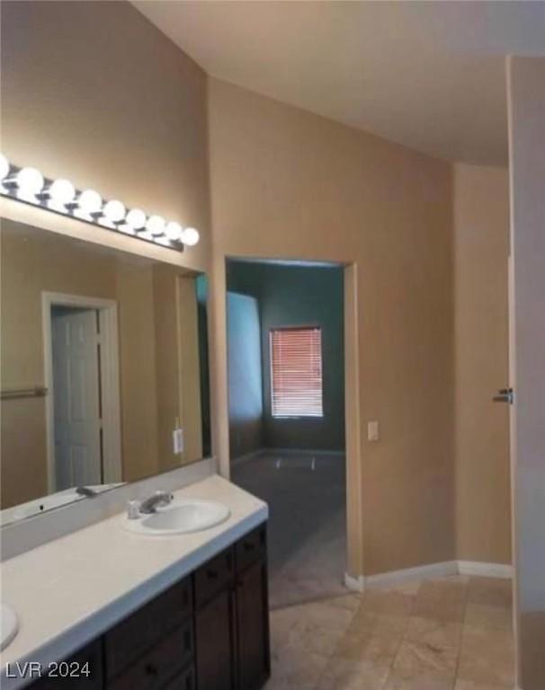 1700 Ravanusa Dr, Henderson, NV 89052 - bathroom featuring a sink, double vanity, baseboards, a tub to relax in, and vaulted ceiling