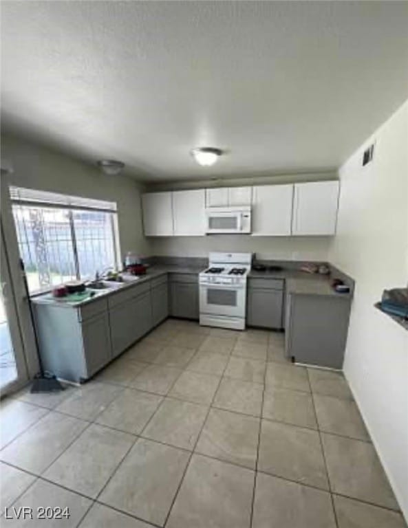 kitchen with gray cabinetry, white appliances, light tile patterned flooring, and white cabinets