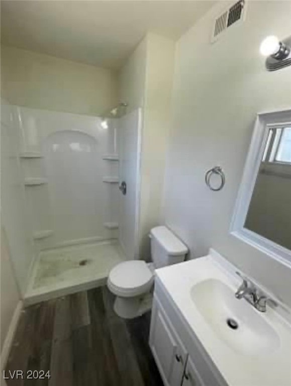 bathroom featuring a shower, wood-type flooring, toilet, and vanity