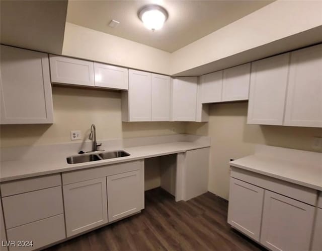 kitchen featuring built in desk, sink, dark wood-type flooring, and white cabinets