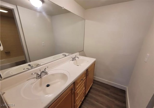 bathroom with dual vanity, washtub / shower combination, and hardwood / wood-style flooring