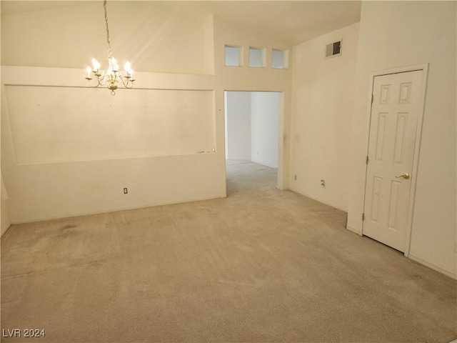 spare room with carpet flooring, high vaulted ceiling, and an inviting chandelier