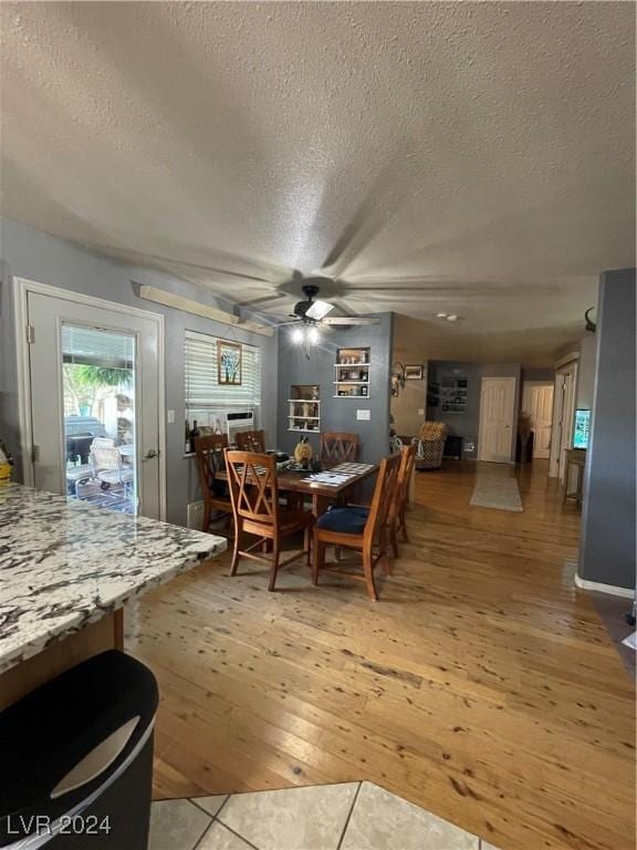 dining space featuring a textured ceiling, a ceiling fan, and light wood-style floors