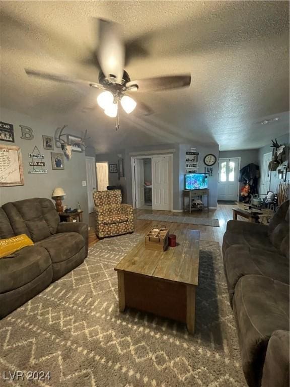 living area featuring a textured ceiling, wood finished floors, and a ceiling fan