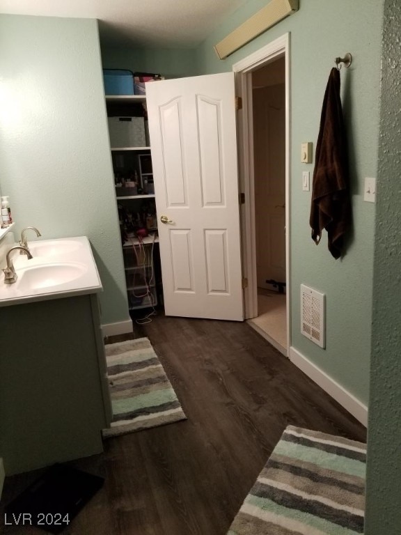 bathroom with visible vents, vanity, baseboards, and wood finished floors