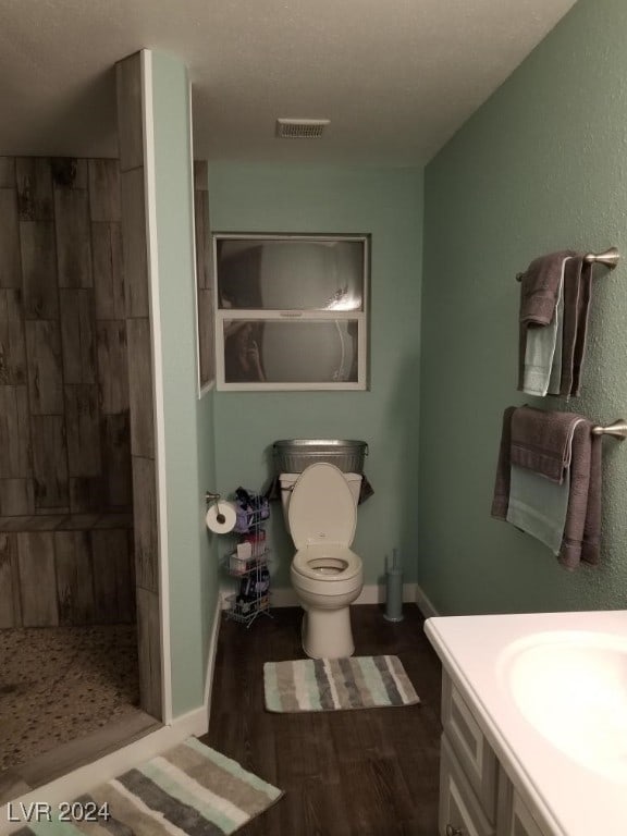 bathroom featuring visible vents, toilet, vanity, a shower stall, and wood finished floors